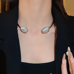 Close-up of French retro choker with irregular metal texture and baroque pearls.