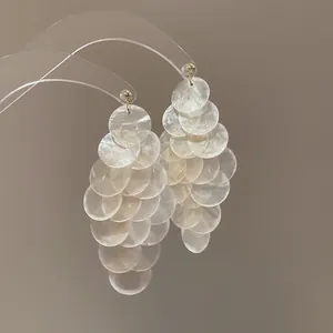 Detail view of pearlescent shell-like cluster dangle earrings with elegant reflection