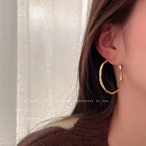 Minimalist gold-plated twisted hoop earrings worn by model