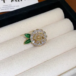Détail d'une broche fleur en zircon plaqué or avec des feuilles en émail vert