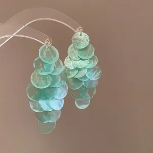 Detail view of mint green sequin cluster drop earrings with gold studs.