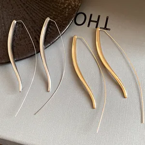Detailed view of minimalist long curved hook earrings in gold and silver finishes