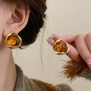 Close-up of vintage amber brown geometric resin earrings with gold-toned metal frame