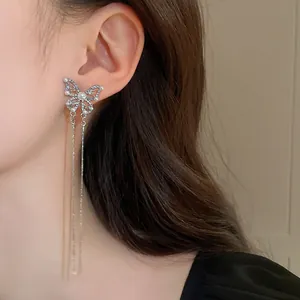 Close-up detail of silver butterfly tassel earrings with pearls and rhinestones on ear