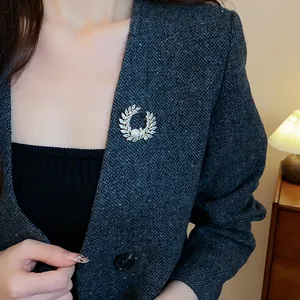 Gros plan d'une élégante broche couronne de feuilles avec perle et zircone sur blazer