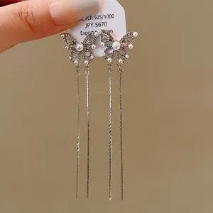 Close-up of silver butterfly tassel earrings with pearls and rhinestones on a white display tag.