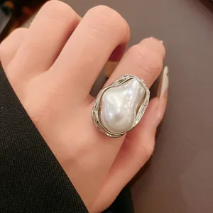 Detail showing a large irregular faux pearl ring with a unique silver textured metal setting