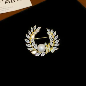 Détail macro d'une élégante broche couronne plaquée or avec zircons et perle centrale