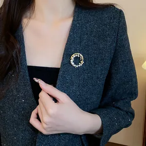 Broche élégante en perles et zircons plaquée or sur un détail de veste en tweed gris