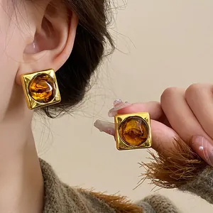 Close-up of vintage gold square earrings with amber resin in a retro Maillard style