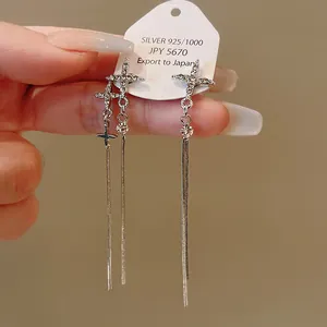 Close-up detail of silver-toned star earrings with long snake chain tassels and rhinestones