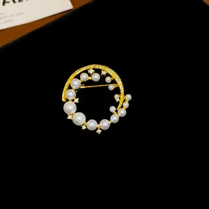 Détail d'une élégante broche dorée ornée de perles et de zircons fins.