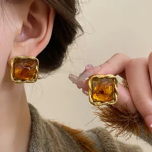 Detailed close-up of vintage amber square stud earrings featuring a gold twisted metal border