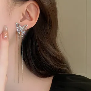 Close-up detail of silver butterfly tassel earrings with pearls and sparkling rhinestones.