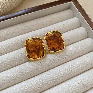 Close-up of vintage brown amber-style resin square stud earrings on white jewelry tray