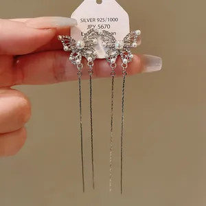 Detailed close-up view of silver butterfly tassel earrings with pearls and rhinestones