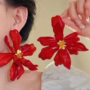 Oversized vibrant red acrylic flower earrings featuring delicate yellow seed bead centers