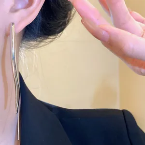 Detailed close-up of a sleek silver teardrop earring featuring a modern minimalist wavy design