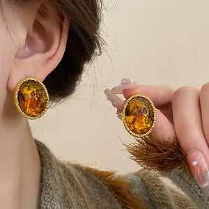 Close-up of vintage oval amber-toned earrings with a textured gold-finish frame
