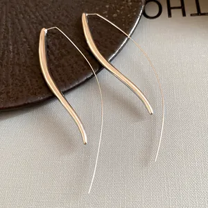 Macro detail of minimalist long curved silver earrings with a high-polished finish