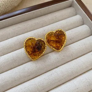 Close-up of vintage heart-shaped earrings with brown resin in a gold frame.