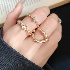 Close-up view of three vintage-style gold rings with heart stones worn on fingers