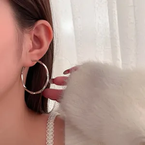 Elegant close-up view of a minimalist silver twisted hoop earring worn by an Asian model