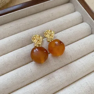 Detailed close-up of vintage Maillard style earrings with gold metal and amber beads