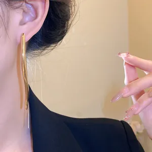 Detailed view of elegant gold water drop long earrings worn by a stylish Asian model