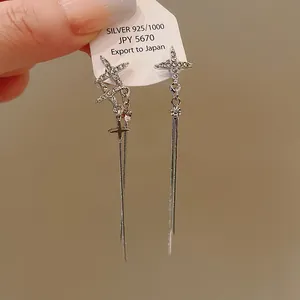 Close-up detail of silver needle tassel earrings with sparkling rhinestone star charms