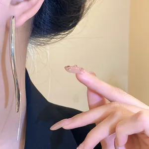 Close-up detail of minimalist silver curved long drop ear hook earring worn by model