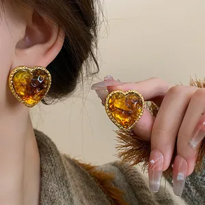 Detailed close-up of vintage heart-shaped earrings in amber resin with gold borders