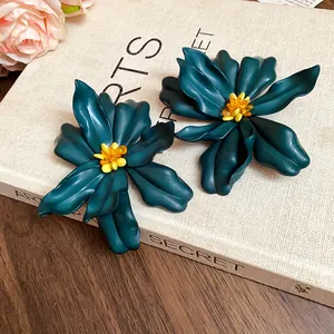 Close-up detail of dark teal oversized acrylic flower earrings with yellow bead centers.