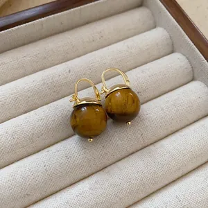 Detailed view of vintage gold earrings with brown tiger eye style beads.