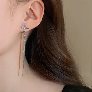 Close-up of sparkling rhinestone cross earrings with long silver tassel chains