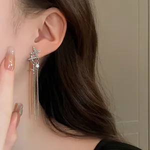 Close-up of elegant silver star tassel earrings with rhinestones worn on the ear