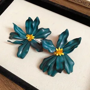 Macro view of teal acrylic flower earrings featuring yellow centers and orange beads
