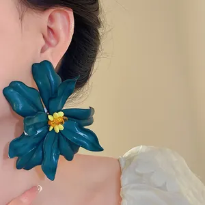 Close-up of exaggerated large blue acrylic flower stud earring with yellow bead center