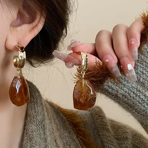 Close-up of retro brown geometric drop earrings on model with warm tones