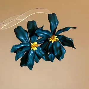 Close-up view of dark teal acrylic flower earrings with intricate yellow beaded centers