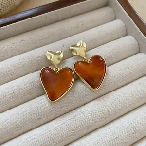 Close-up of vintage brown resin heart earrings with gold-toned metal tops