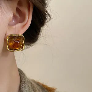 Close-up of vintage brown square stud earring with a gold twisted metal border style