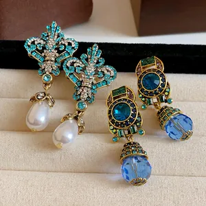 Close-up of vintage rhinestone earrings with teardrop pearl and blue crystal drops