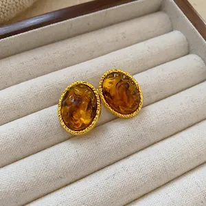 Close-up of vintage Maillard style amber oval earrings in a beige velvet jewelry box