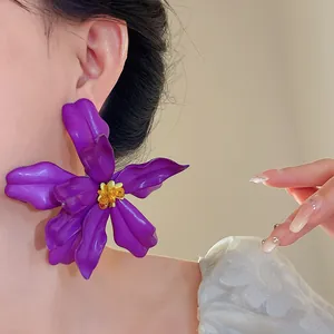 Close-up detail of an oversized purple acrylic flower stud earring with silver needle