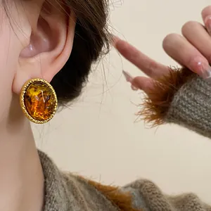 Close-up of vintage Maillard style oval amber resin earrings with gold textured frame
