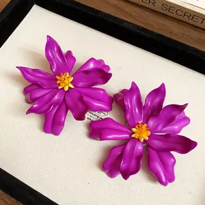 Close-up of purple acrylic flower statement earrings with yellow seed bead centers.
