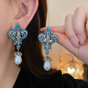 Close-up of vintage blue rhinestone earrings with pearl drops worn on an ear