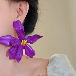 Close-up detail of an oversized purple acrylic flower stud earring worn on the ear