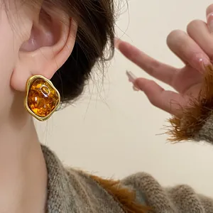 Detail view of a vintage amber resin earring with gold-tone irregular metal border